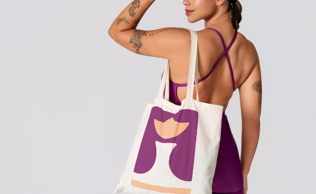 mulher usando macaquinho de cor magenta usando eco bag com logo da Liss Fitness